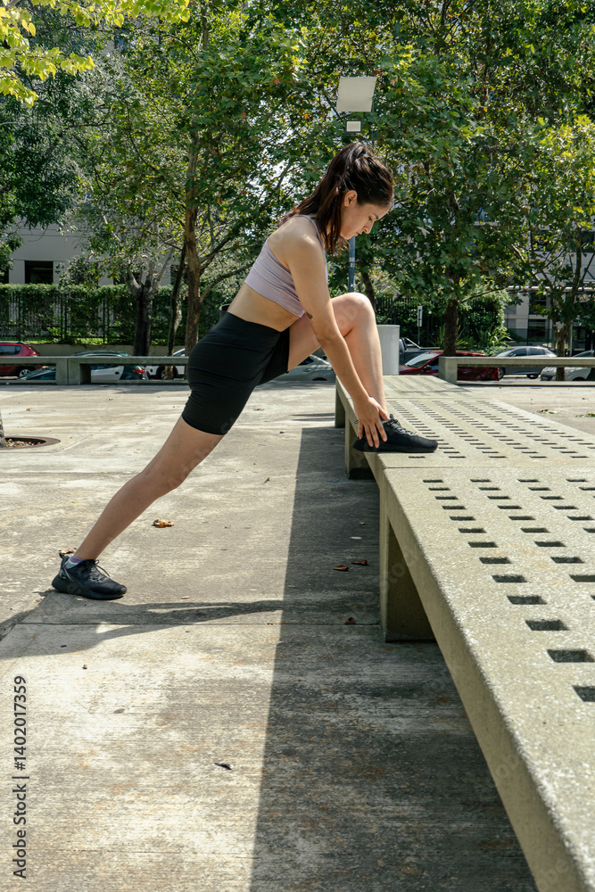 Young sporty woman stretching legs in a city park
