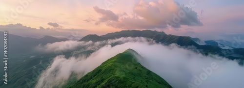 A panoramic view of lush green mountains enveloped in mist during sunset.