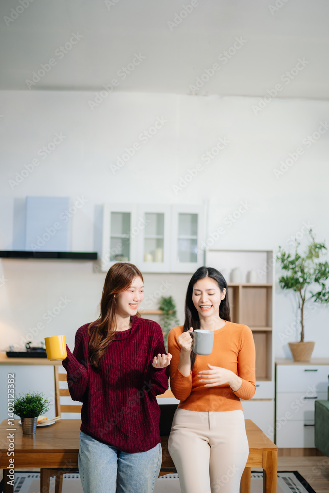Two young Asian women brainstorming over coffee with a laptop and notebook at home. Two young Asian women brainstorming over coffee with a laptop and notebook at home.