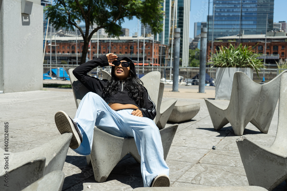 Latin woman relaxing on modern concrete chair in puerto madero, buenos aires