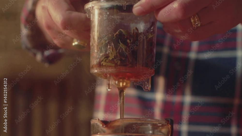 Close-up of a hand picking dried tea leaves to brew with a glass tea press. Ideal for themes of traditional tea rituals, craftsmanship, and slow-living moments.