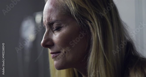 Close-up of woman with pained expression and closed eyes, emotional moment during treatment or diagnosis in medical setting