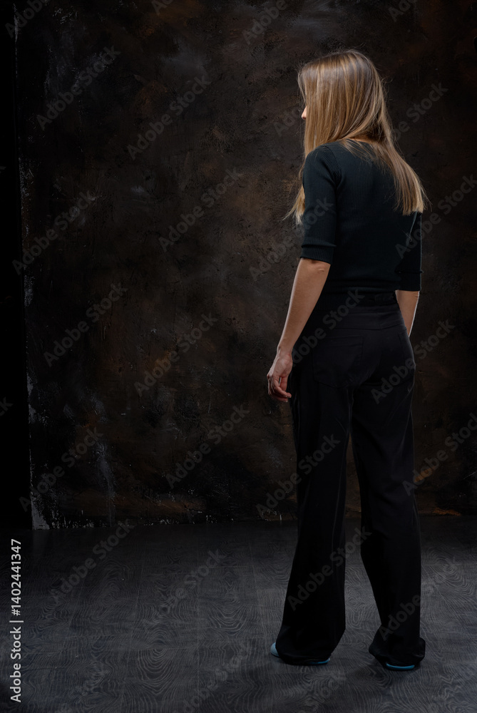 Woman Standing In a Dimly Lit Studio With a Textured Background.. Woman Standing In a Dimly Lit Studio With a Textured Background..
