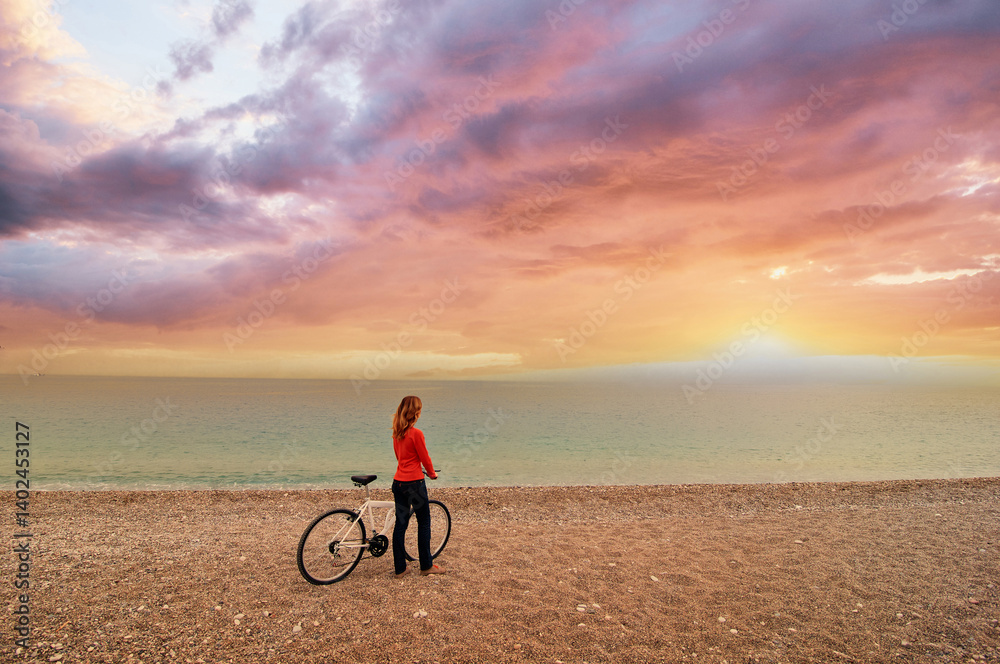 Fototapeta premium Woman Admiring Scenic Beach Sunset with Bicycle in Beautiful Setting..