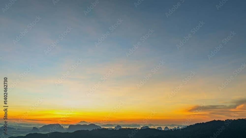 Aerial hyper lapse view of serene sunset casts a golden glow over rolling hills and distant mountain peaks, creating a peaceful and atmospheric landscape with layers of mist and soft light.