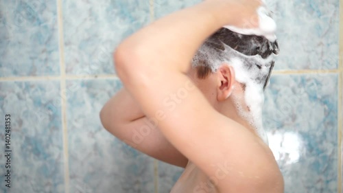 Teen boy soaping his head and dancing in the bathroom close-up