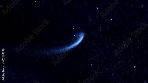 A blue streak of light moving across a dark background with small particles