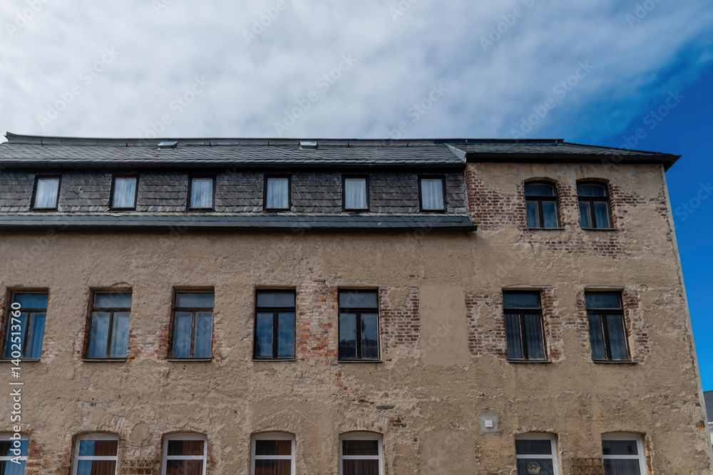 Old stone building with multiple windows under a cloudy sky in a quaint town setting Old stone building with multiple windows under a cloudy sky in a quaint town setting