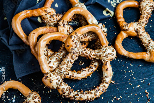 Obraz na płótnie Fresh prepared homemade soft pretzels. Different types of baked pretzels with seeds on a black background w salonie