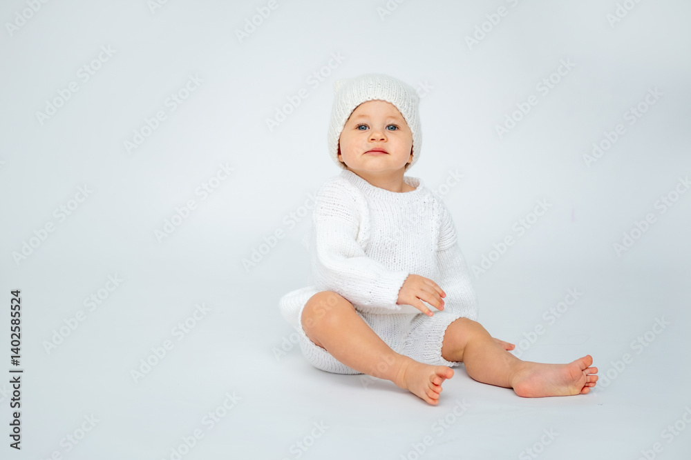 A baby boy on a white isolated background with a place for text is sitting in white knitted clothes with a hat. A small child in a winter sweater, space for text A baby boy on a white isolated background with a place for text is sitting in white knitted clothes with a hat. A small child in a winter sweater, space for text