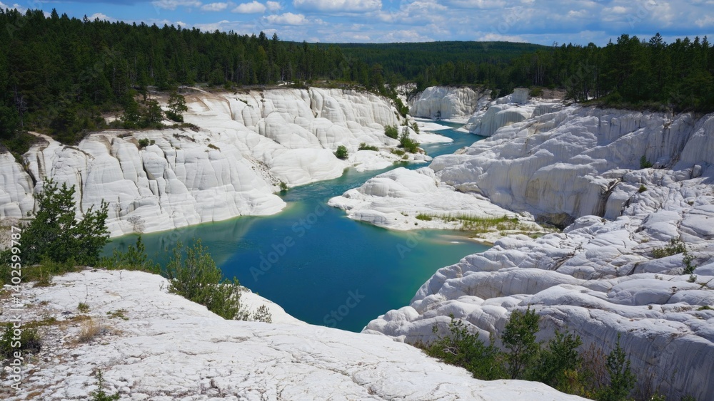 A picturesque view of a clear river flowing through a canyon surrounded by lush forest and rugged rocky cliffs, revealing unique geological formations indicative of mineral deposits.
