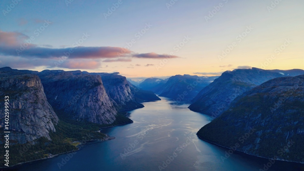Vibrant hues of sunrise over a tranquil fjord. Scenic Norwegian mountain landscape with calm waters.