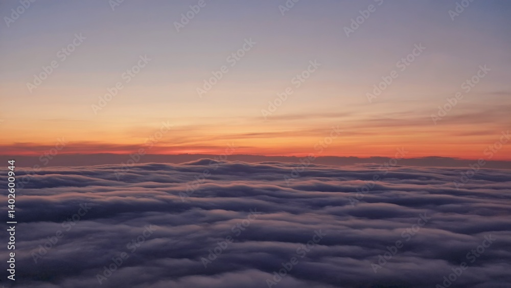Aerial view of clouds at sunset from an airplane. Silhouette of clouds against orange sky