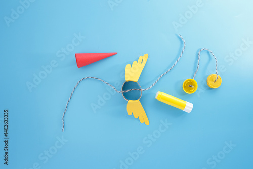 craft materials. Red Paper Cone, Cardboard Tube, Glue Stick, Bottle Caps with String, fun and creative DIY craft project, educational activities. use everyday items for imaginative crafting. photo