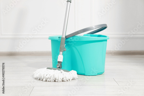 Obraz na płótnie String mop and bucket on wooden floor near white wall w salonie