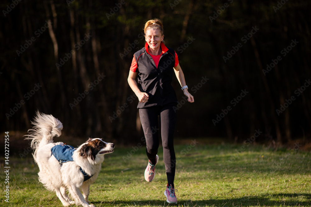 fit happy woman running with her dog outdoors