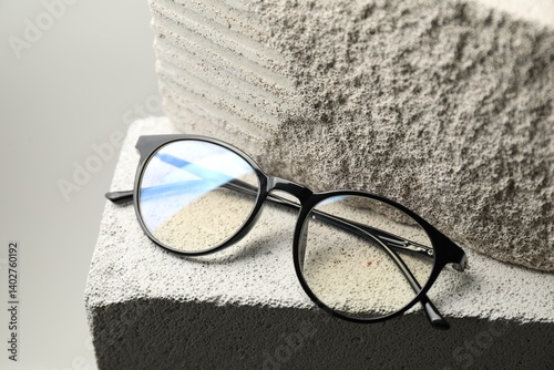 Stylish glasses on stone surface against light grey background, closeup photo
