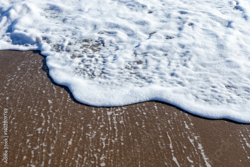 Fototapeta Naklejka Na Ścianę i Meble -  Close-up of sea foam washing over sandy beach on a sunny spring day. Side, Turkey, Mediterranean coast
