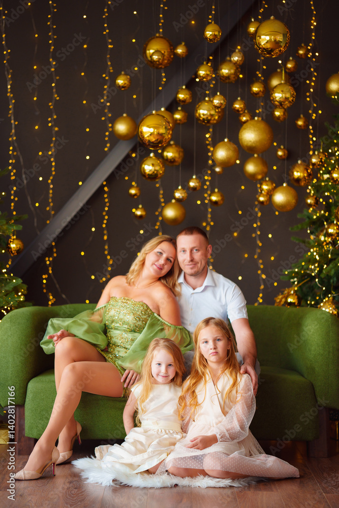 A happy family in elegant clothes on a green sofa at the Christmas tree.