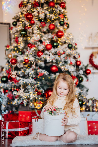 Obraz na płótnie Beautiful little girl with a gift at the Christmas tree. w salonie
