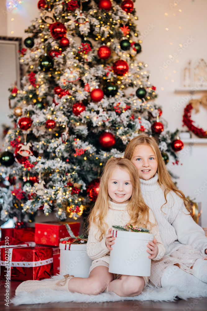 Two cute sisters at the christmas tree with gifts