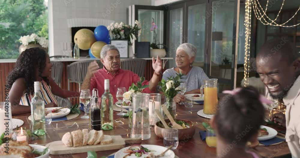 Diverse family raising glasses around dining table, celebrating joyful gathering together, at home