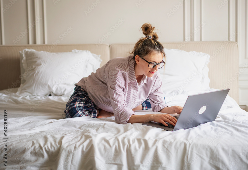 Beautiful smiling woman using laptop in bed