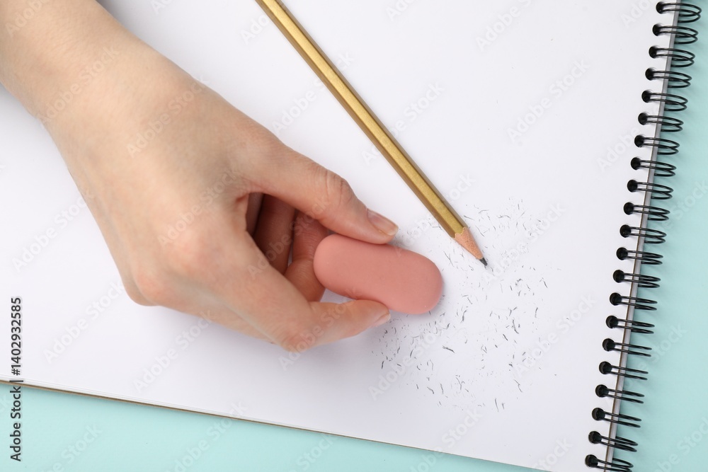 Woman rubbing eraser against paper at light blue table, top view Woman rubbing eraser against paper at light blue table, top view
