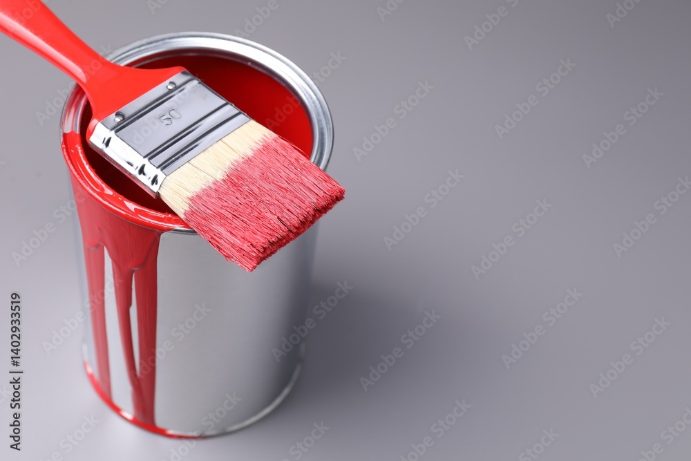 Can of red paint and brush on grey background, closeup. Space for text