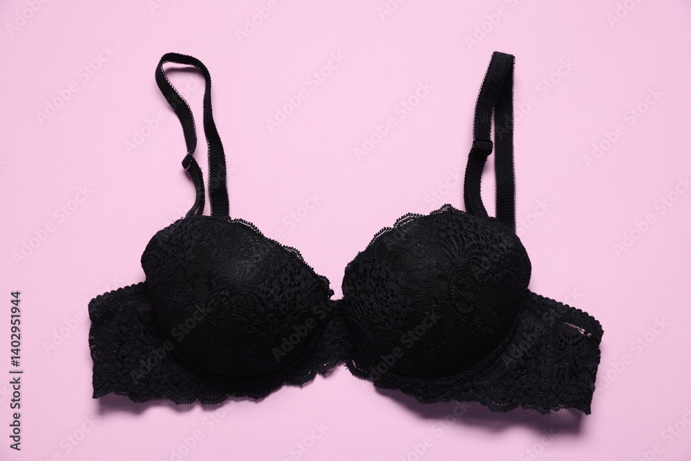 One black lace bra on pink background, top view
