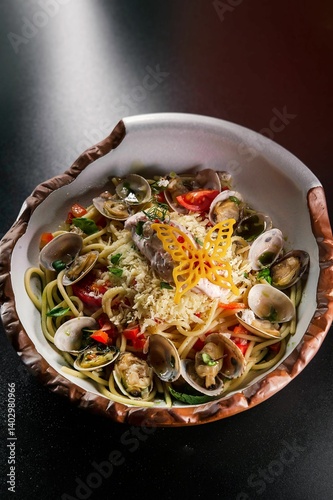 Creative seafood vongole pasta spaghetti with cherry tomatoes and parsley served on the white designers plate