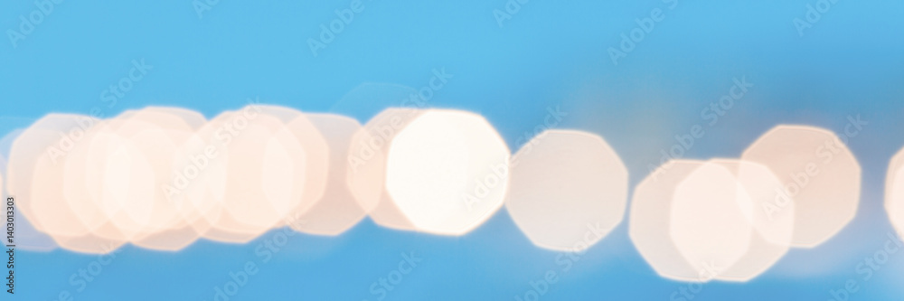 Beautiful blurred festive background with bright highlights and bokeh. Shallow depth of field. Spectacular bright light spots on a blue background. Winter wide panoramic background for design.