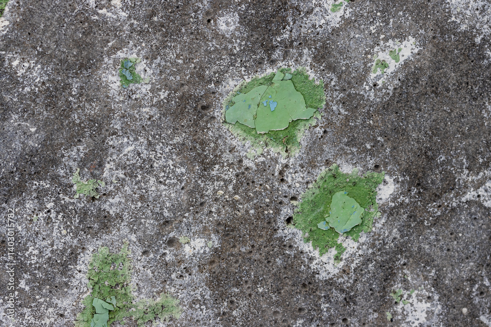 Green peeling paint on the wall. Old concrete wall with cracked flaking paint. Weathered rough painted surface with patterns of cracks and peeling. High resolution texture for background and design.