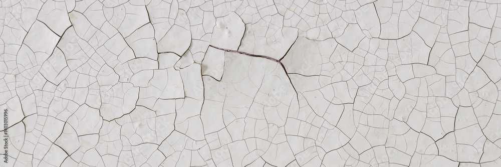 Peeling paint on the wall. Panorama of a concrete wall with old cracked flaking paint. Weathered rough painted surface with patterns of cracks and peeling. Wide panoramic grunge texture for background