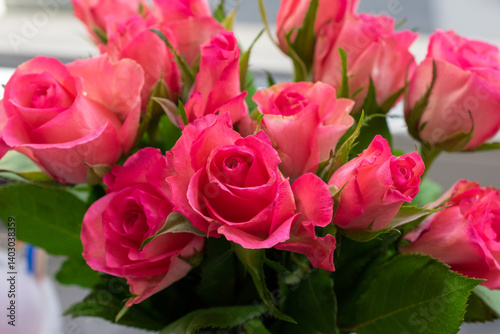 Bouquet of pink roses. The roses are in a vase. The vase is on a table.