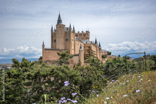 Alcazar of Segovia from Beautiful Viewpoint with Flowers in Spain. Architectural Exterior of Medieval Castle in Europe.