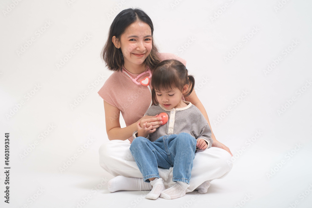A joyful mother and her adorable child sitting together in a studio setting, sharing a tender moment of playfulness and love. A joyful mother and her adorable child sitting together in a studio setting, sharing a tender moment of playfulness and love.
