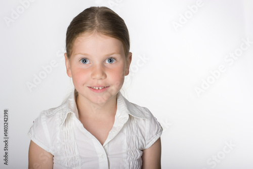 surprised fair-haired blue-eyed seven year old girl in white shirt on white background