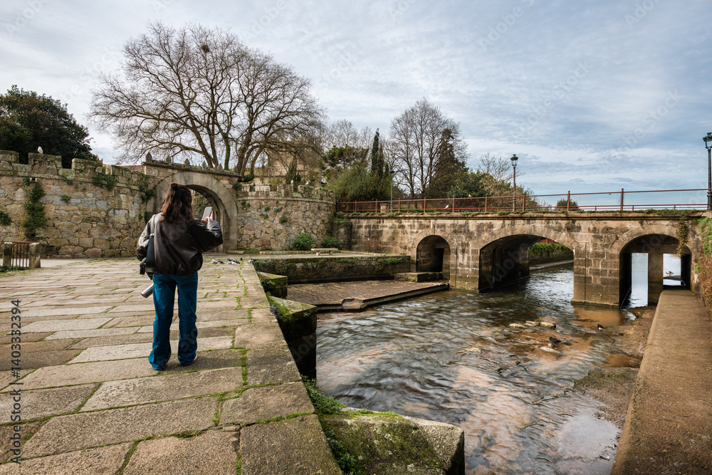 Fototapeta premium Woman using smartphone to photograph historic architecture outdoors in Spain