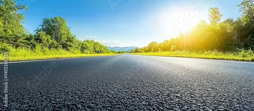 Asphalt road under bright sunlight stretching toward distant hills, green fields on both sides with scattered trees, wide-angle composition with gradient blue sky, serene rural landscape.