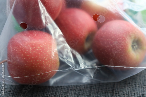 A bag of apples sitting on a wooden table.