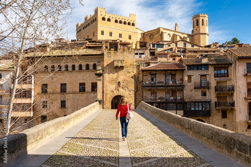 Tourist woman crossing the medieval stone bridge that leads to the town of Valderrobres, Teruel.