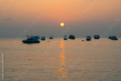 Silhouette of boats at sunset tropical beach at Maldives Island.