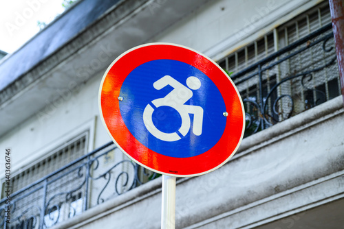 A vibrant red and blue sign featuring a clear icon of a person in a wheelchair on it, indicating accessibility features for individuals