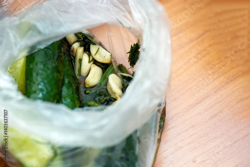 Peeled garlic cloves and sliced lightly salted cucumbers in a plastic bag, ready for quick pickling or cooking preparation