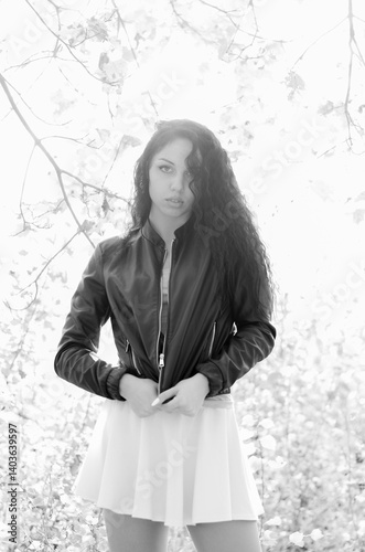 Close-up portrait of a fantastic young model girl posing in the park on a sunny day. Black and white photo.