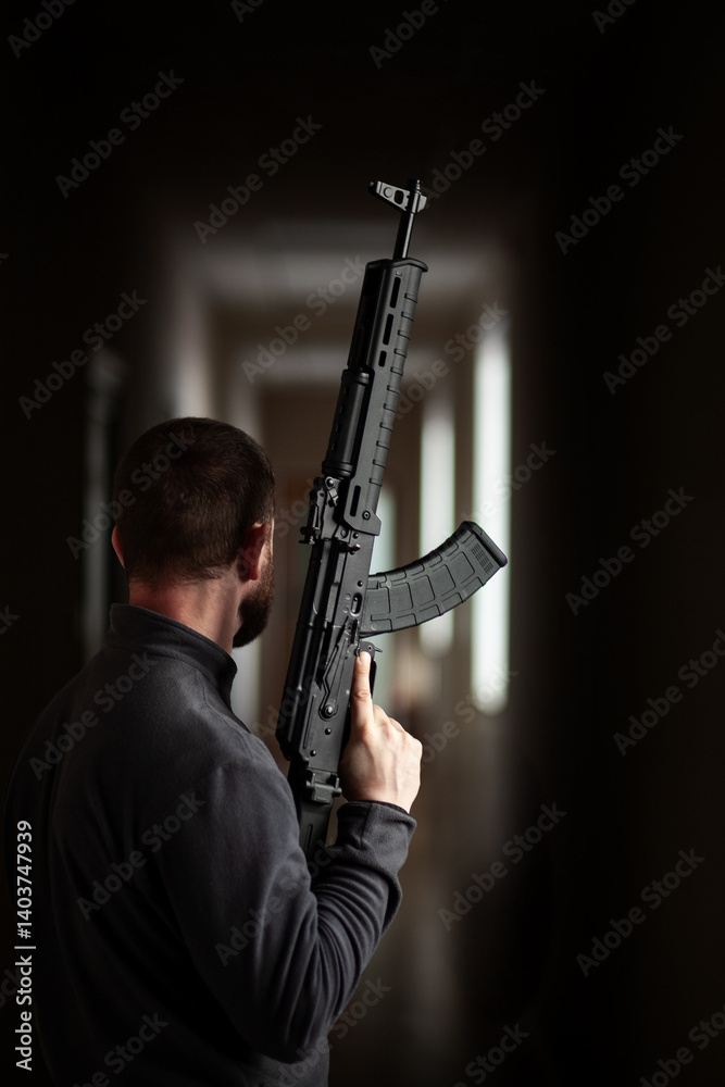 man holding black tactical rifle in dim corridor interior man holding black tactical rifle in dim corridor interior