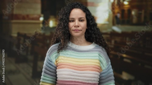 Wallpaper Mural Young hispanic woman extends fist towards camera in indoor church setting, showcasing vibrant sweater and curly hair in a serene spiritual environment. Torontodigital.ca