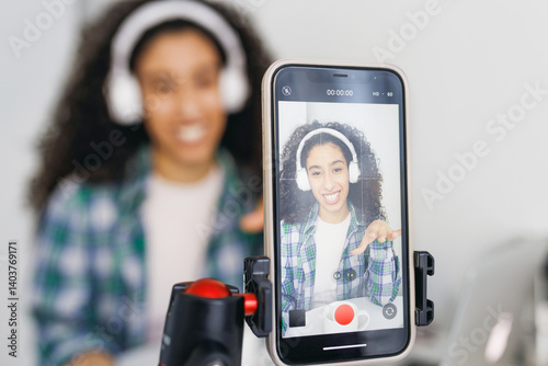 Bild auf Leinwand Selective focus on smartphone camera recording video of young mulatto curly-hair