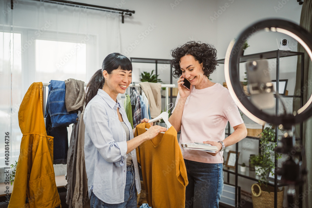 Two diversity woman sell clothes live stream on mobile phone at home